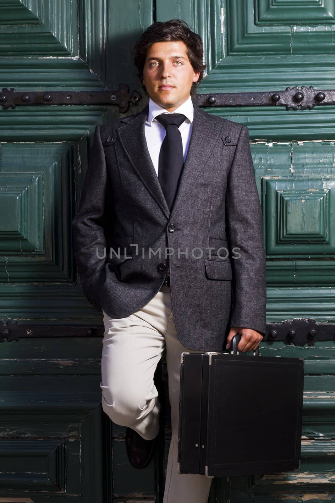 View of a happy business man with a black suitcase on a European city.