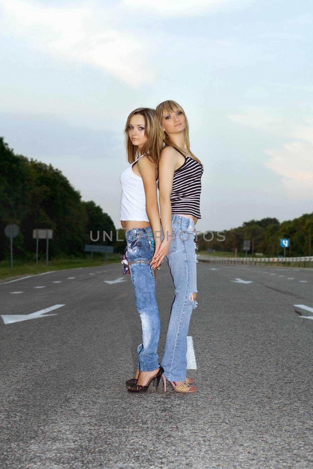 Two beautiful girls standing on a road 