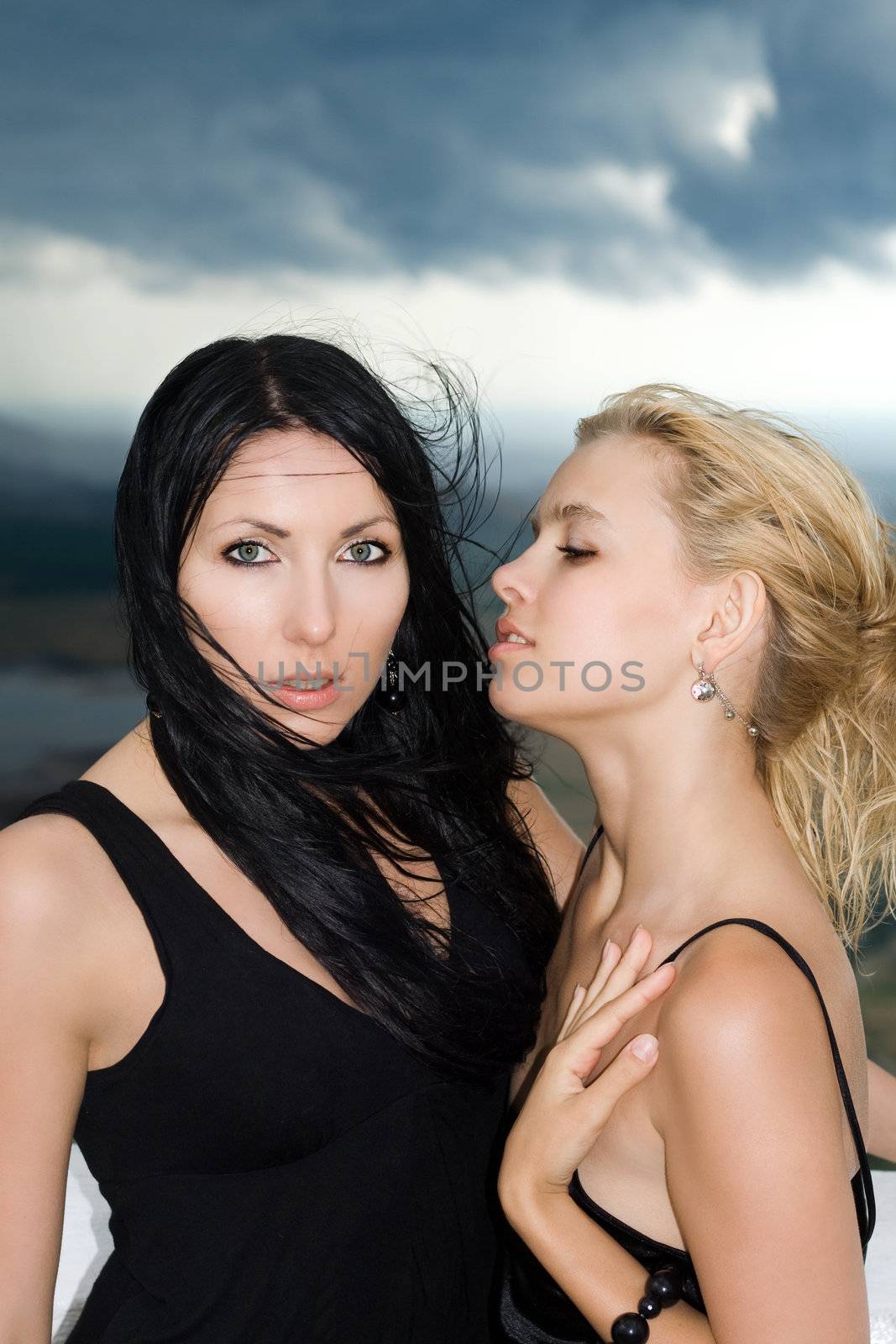 Portrait of the two young women against the cloudy sky