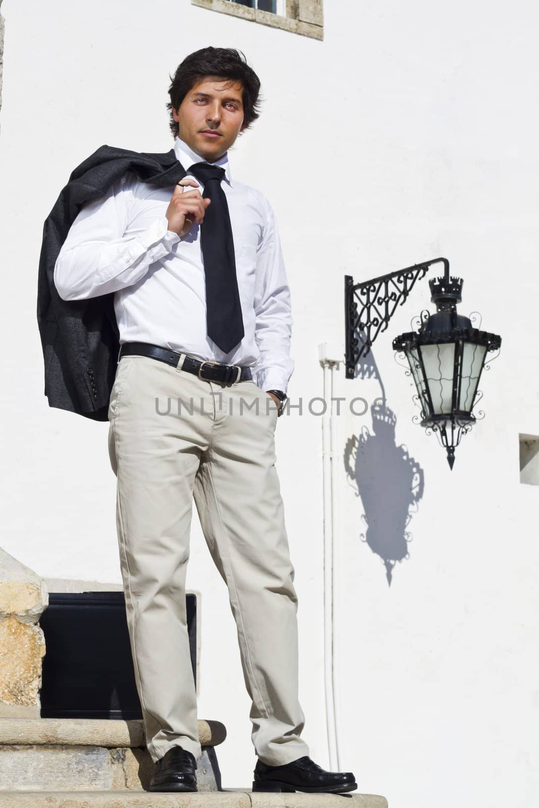 View of a happy business man with a black suitcase on a European city.