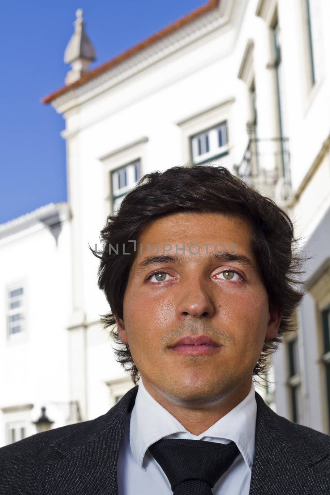 View of a happy business man with a black suitcase on a European city.