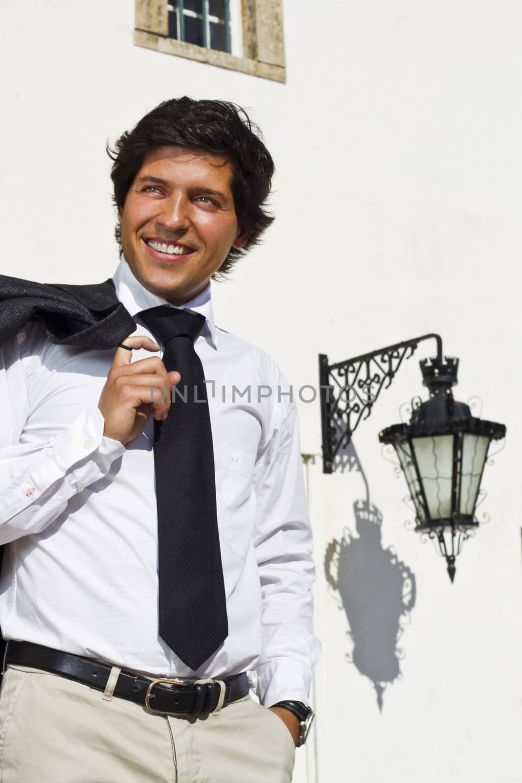 View of a happy business man with a black suitcase on a European city.