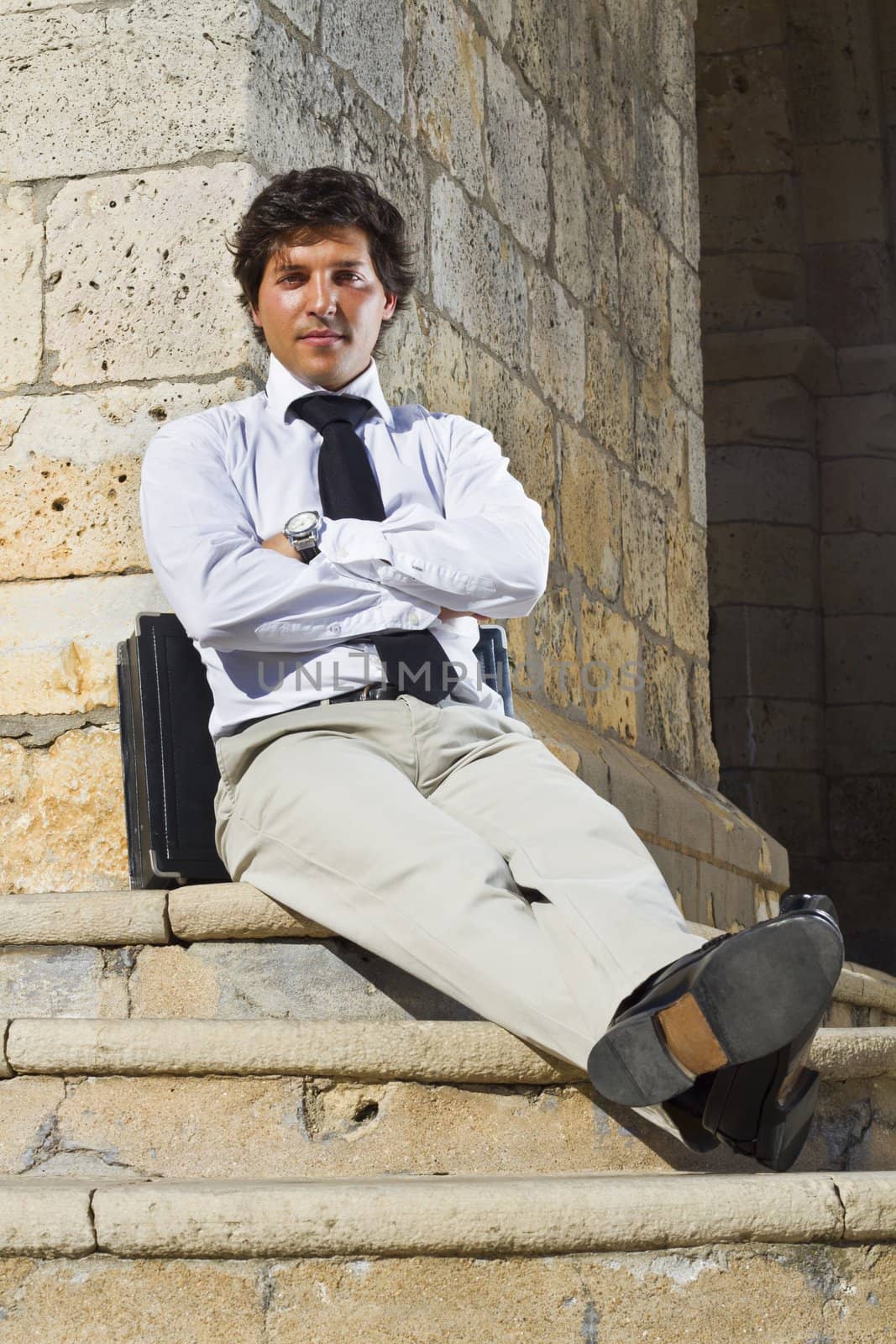 View of a happy business man with a black suitcase on a European city.