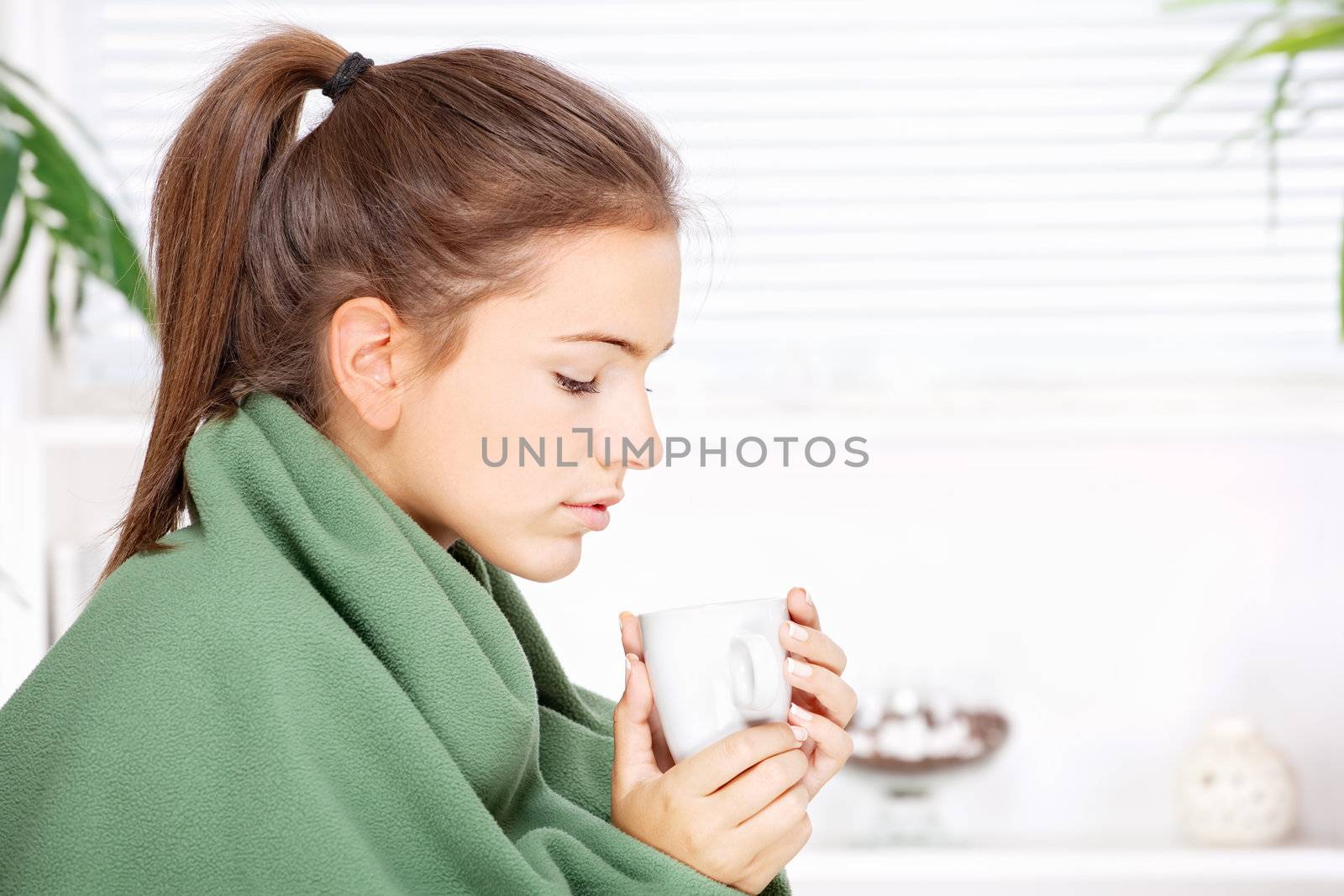 woman drinking tea  at home covered with blanket by imarin