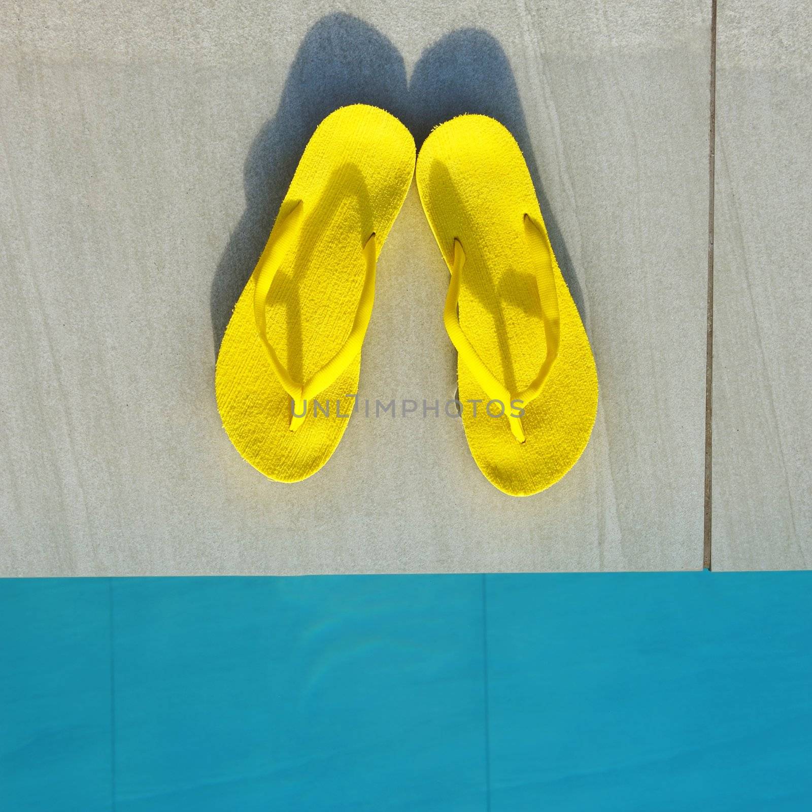 Yellow sandals by a swimming pool 