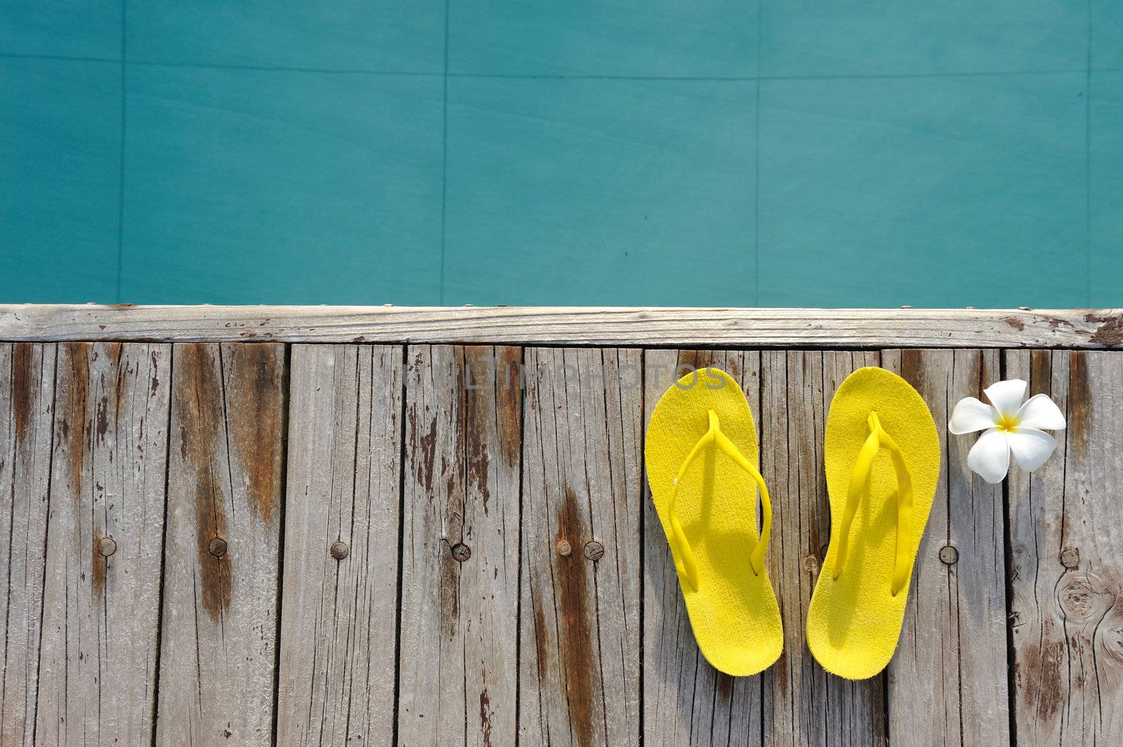 Yellow sandals by a swimming pool 