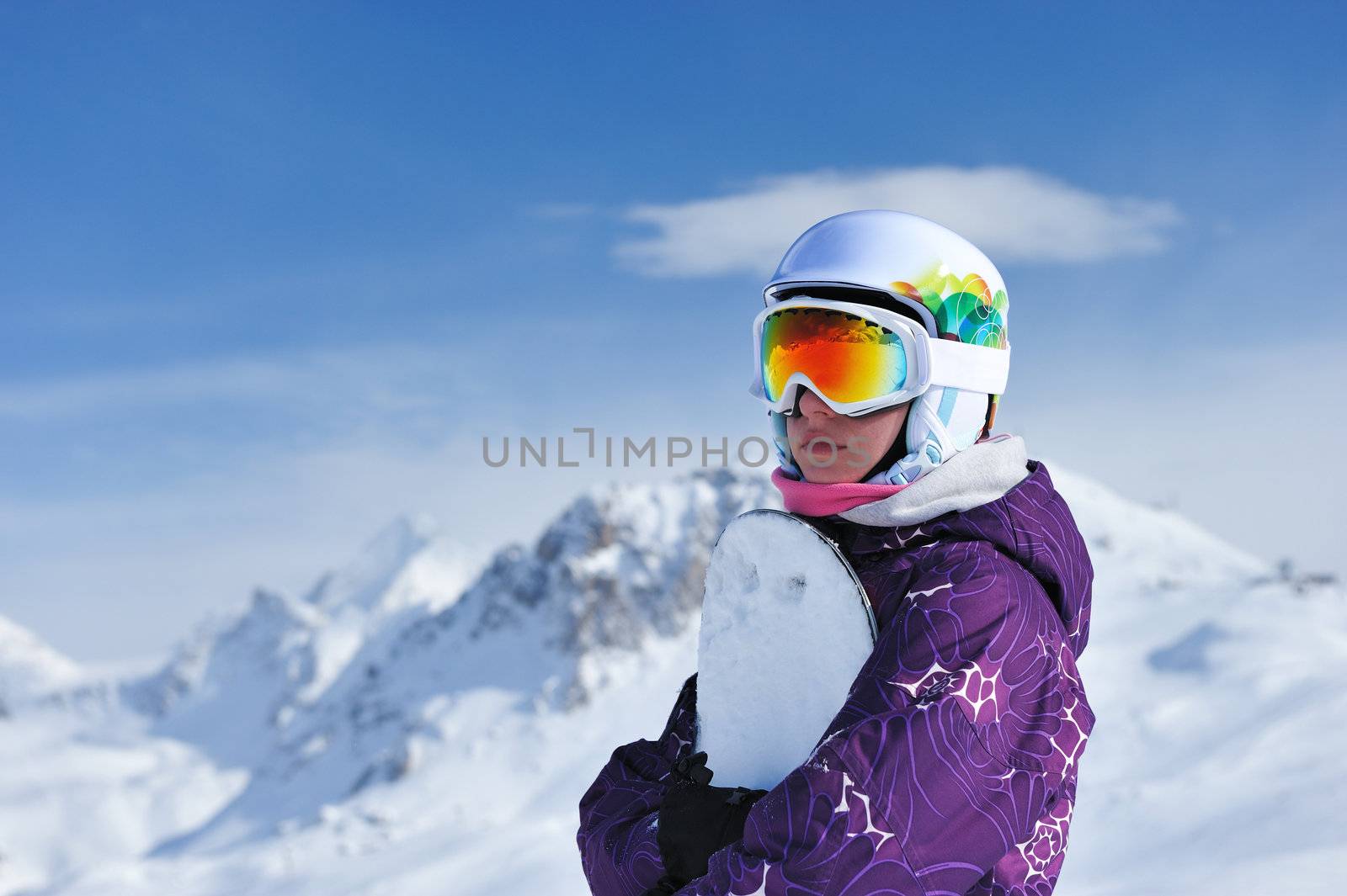 Woman holding snowboard with mountains in background. No brandnames or copyright objects. 