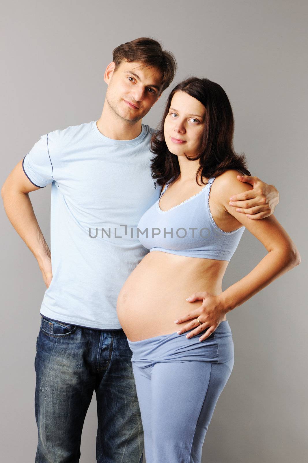 Happy pregnant couple over grey background