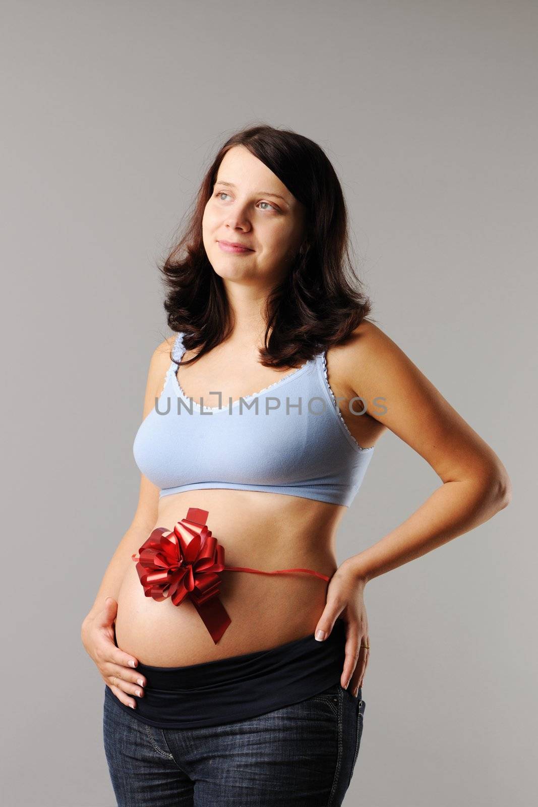 Portrait of a pregnant woman with wrapping bow on her her belly