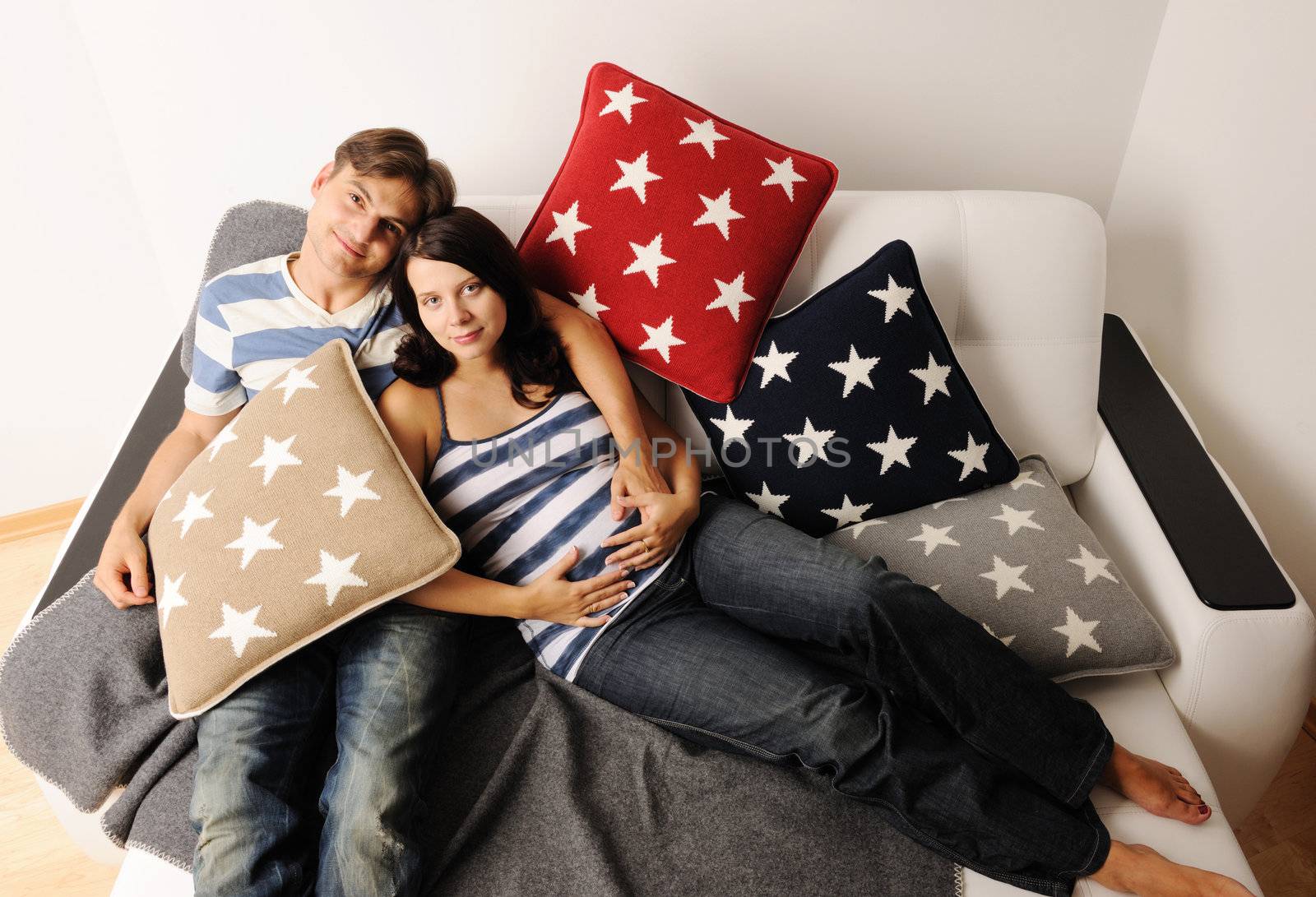 Happy pregnant couple on a sofa