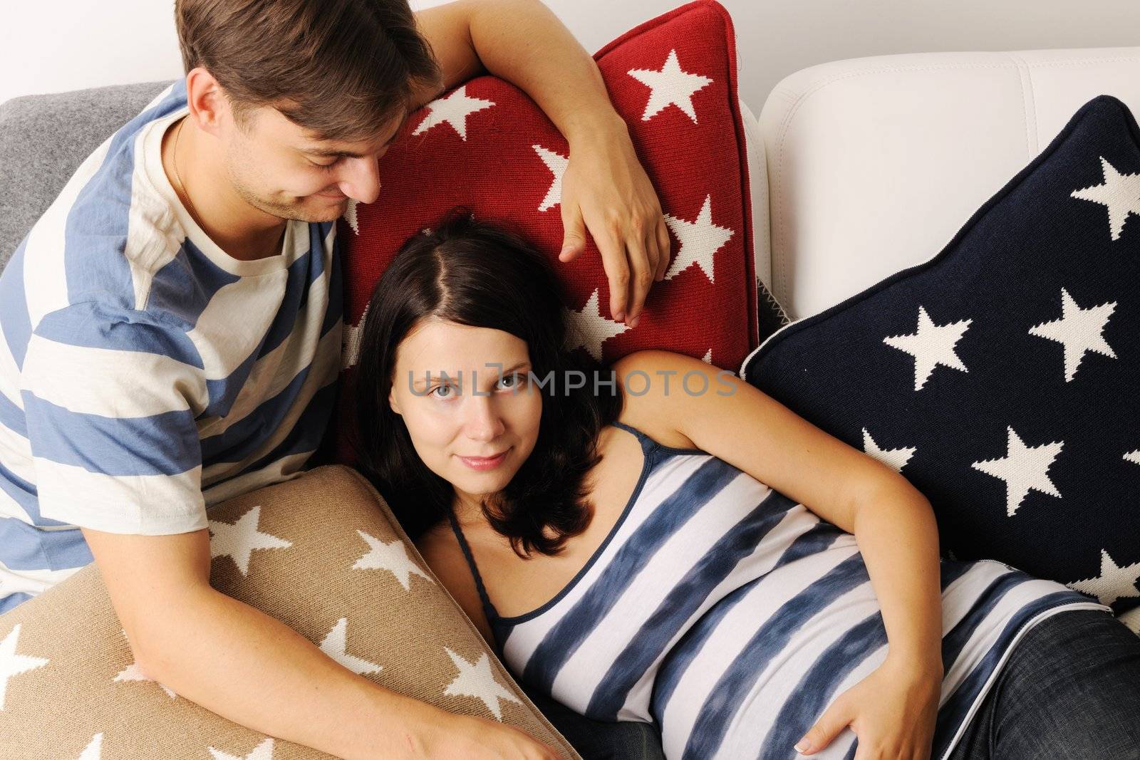 Happy pregnant couple on a sofa
