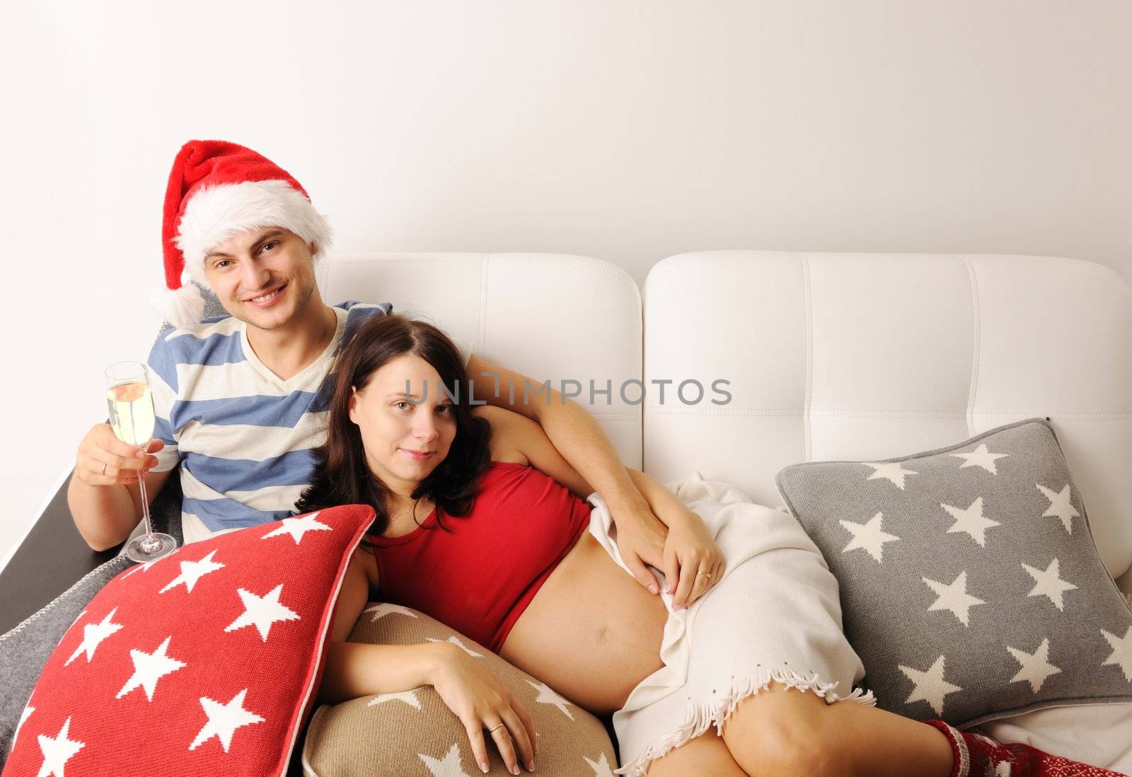 Happy pregnant couple at christmas on a sofa