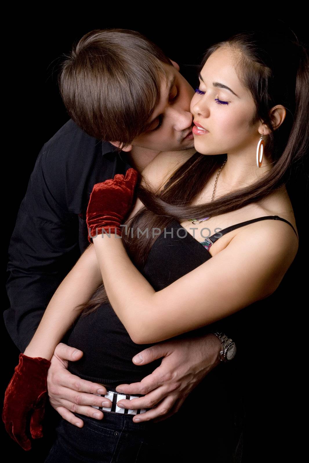 Young man kissing pretty woman. Isolated on black