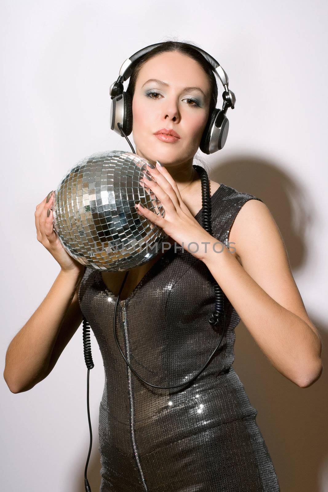 Portrait of attractive young woman in headphones with a mirror ball