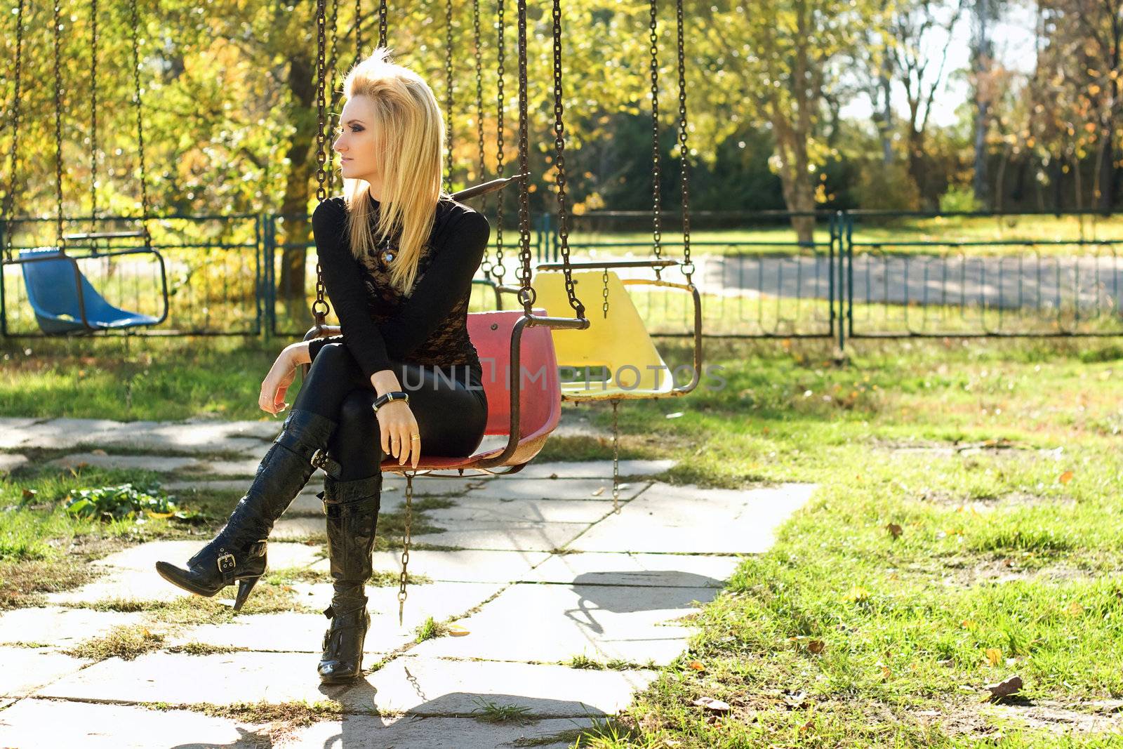 Young pretty blonde sitting on a carousel outdoors