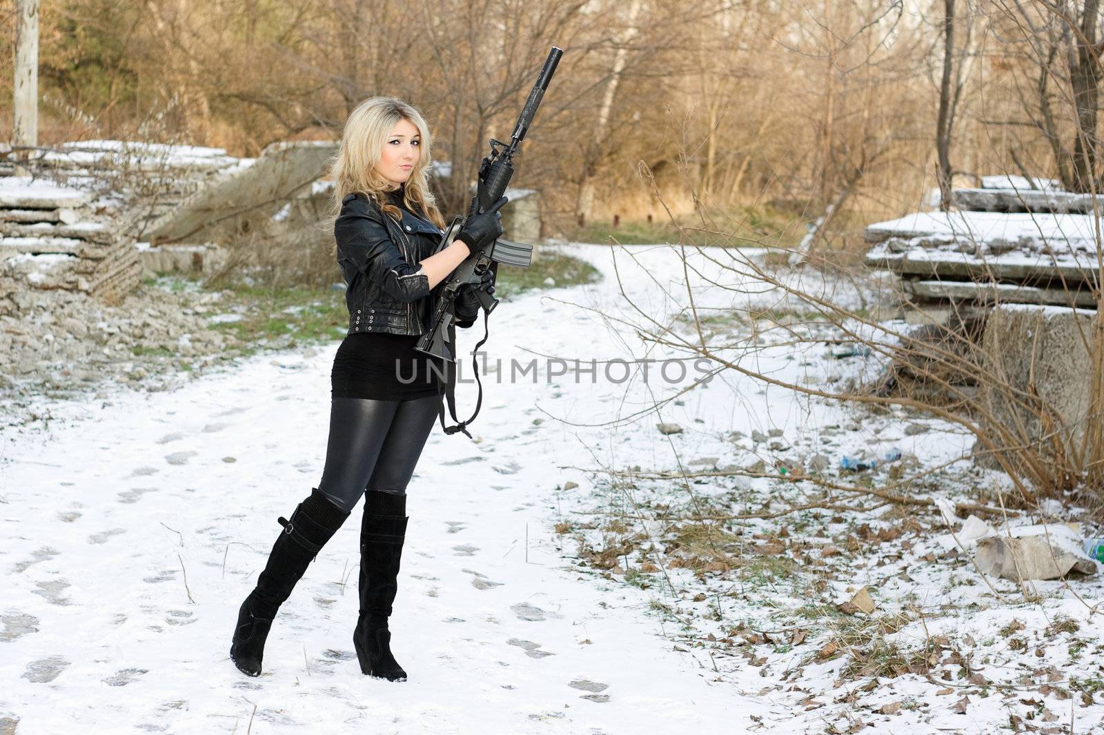 Beautiful young woman with a gun outdoors