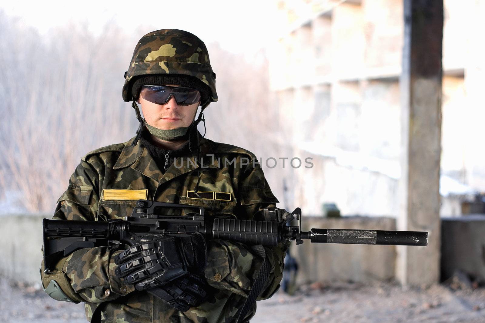 Handsome man with a rifle in front of neglected house