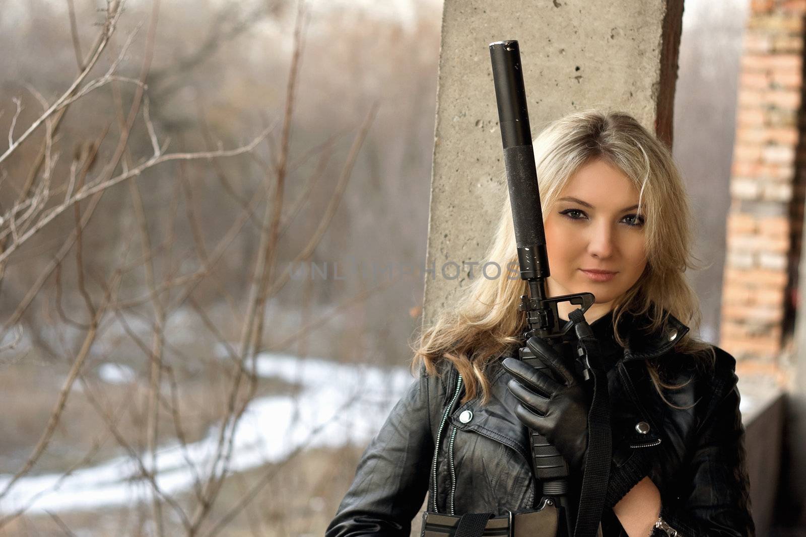 Beautiful girl with a big gun in front of the winter forest