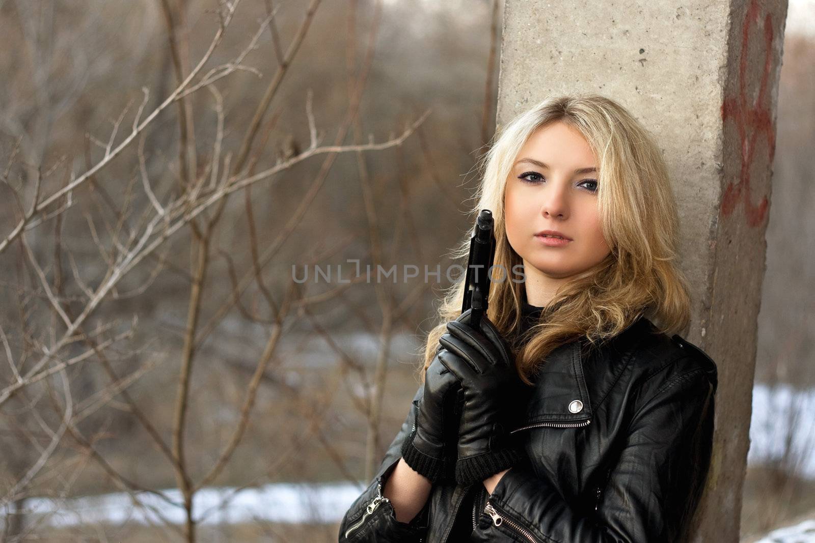 Sensual young woman holding a weapon in front of the winter forest