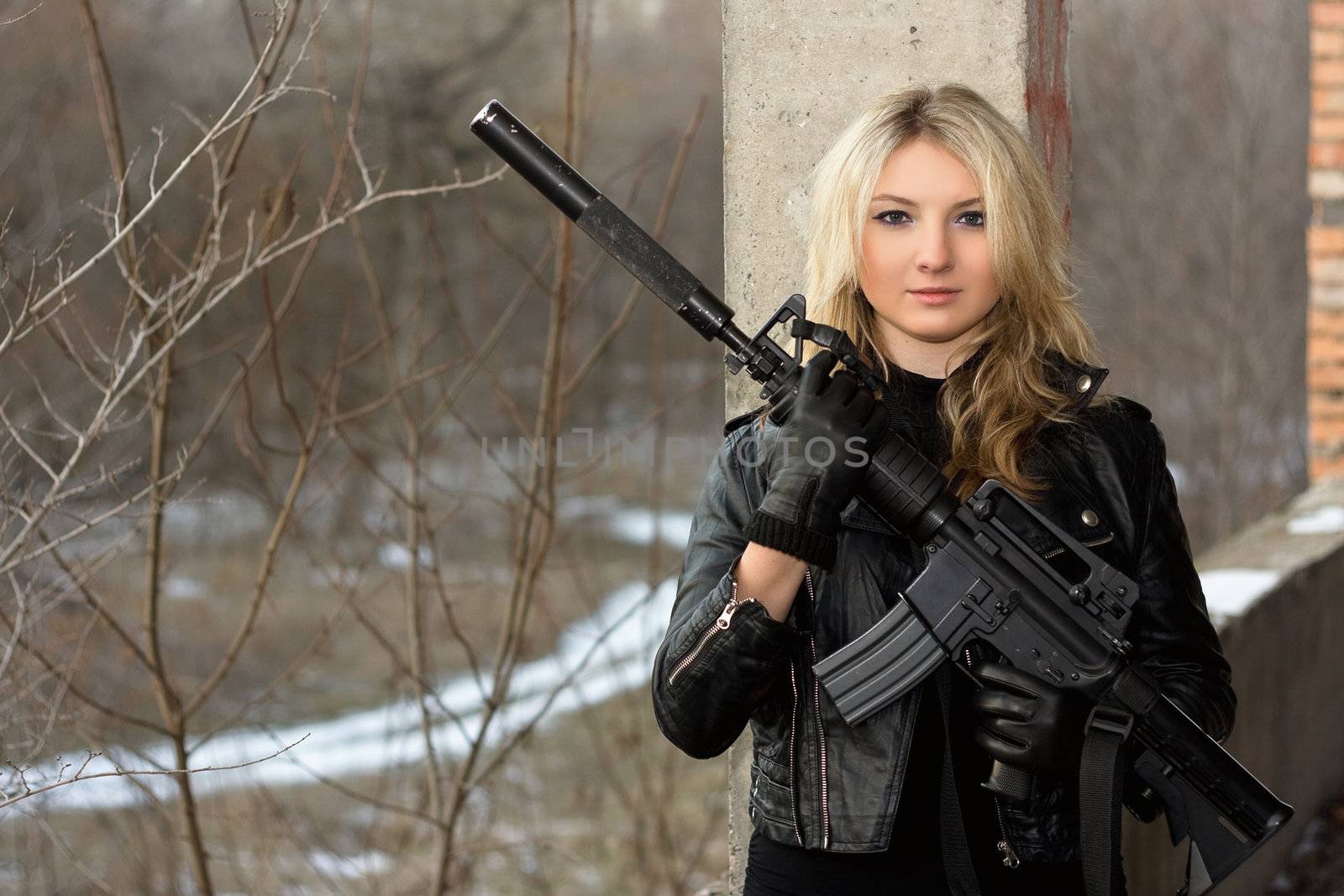 Scared girl in leather jacket with a big rifle