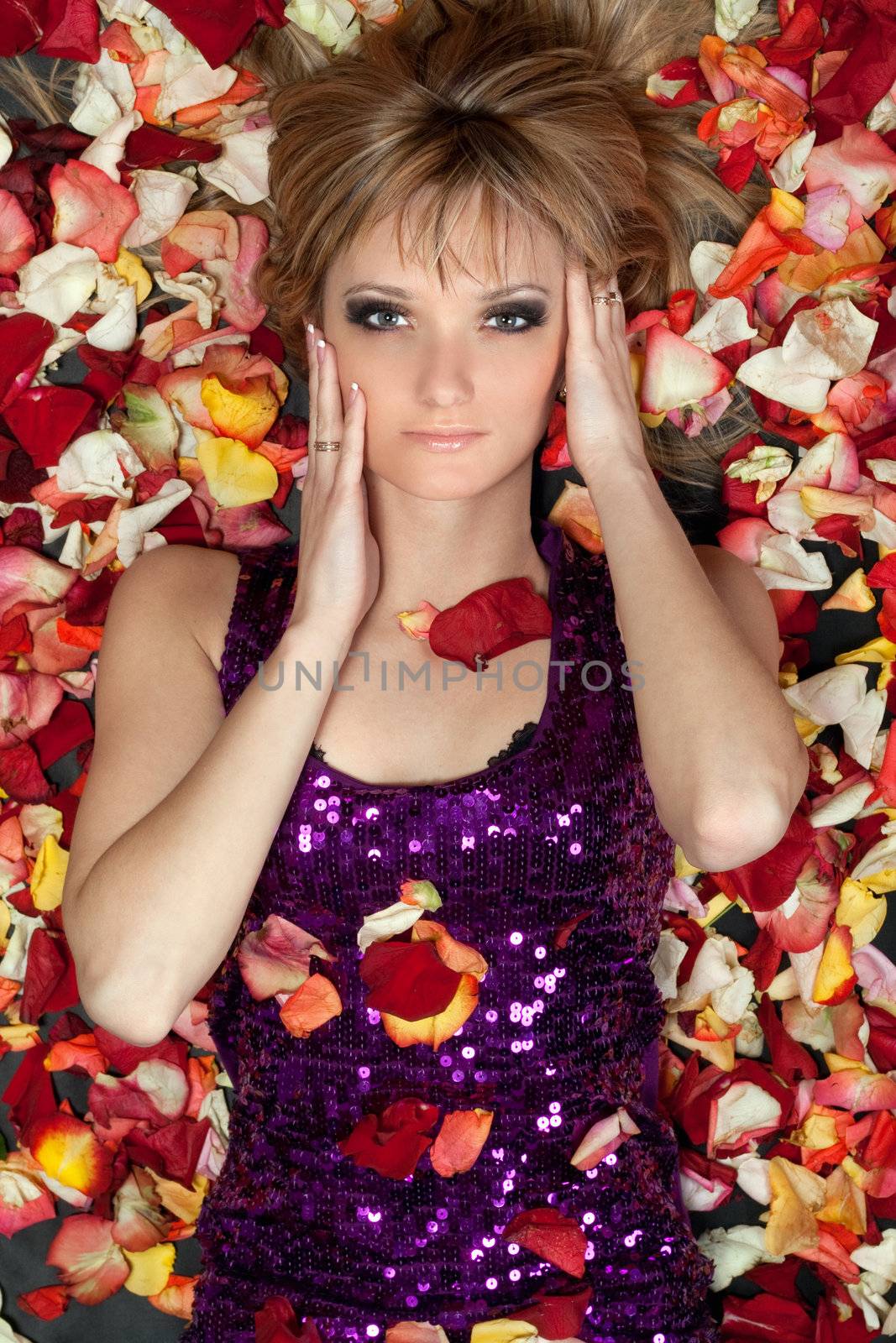Portrait of pretty young blonde lying in rose petals