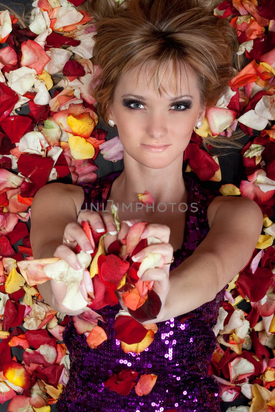 Portrait of charming young blonde lying in rose petals