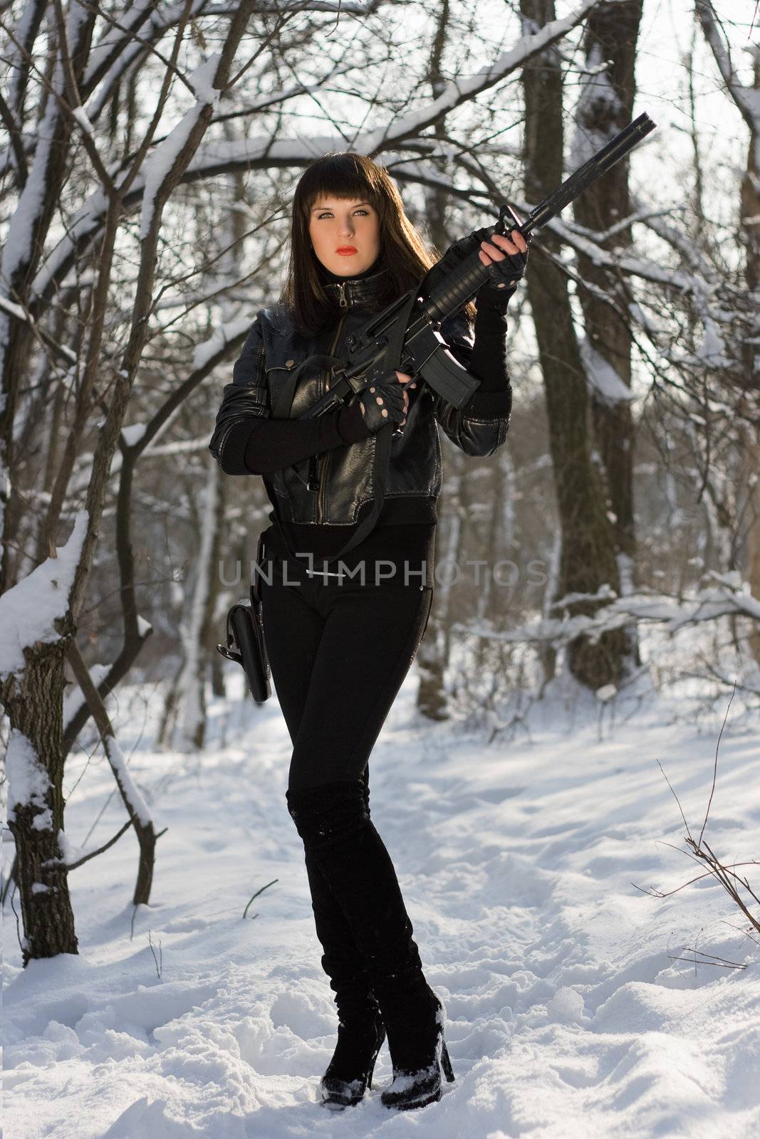 Attractive young woman with a rifle in winter forest