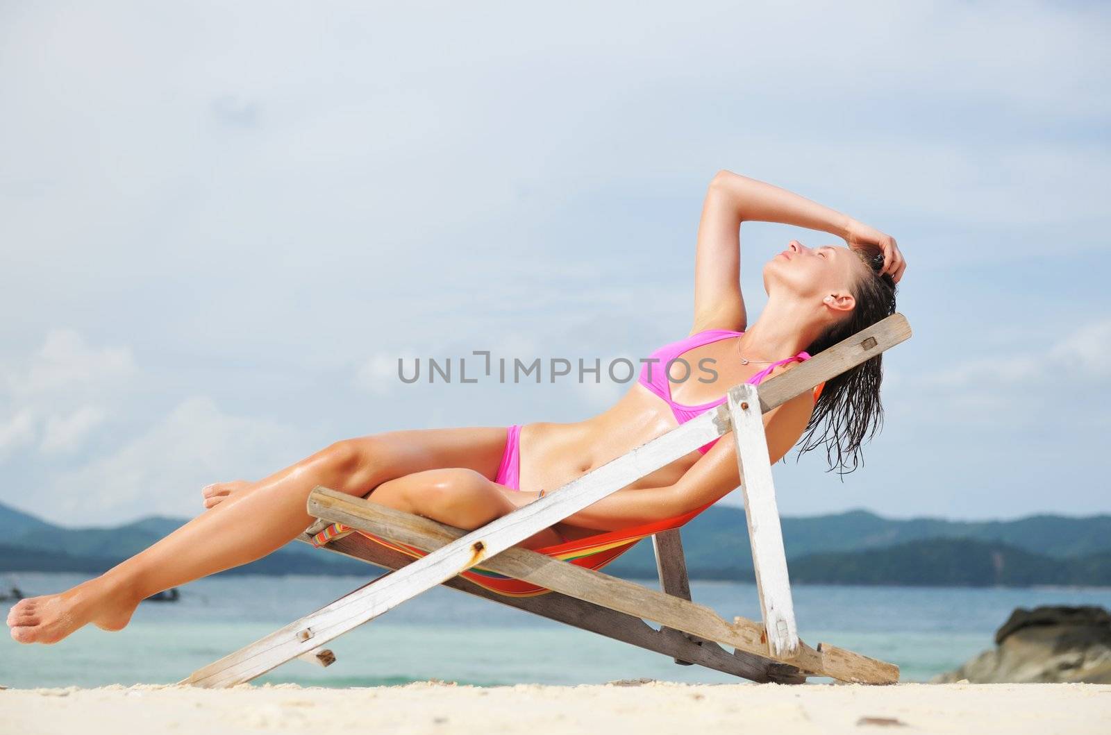 Girl on a tropical beach sitting in chaise lounge