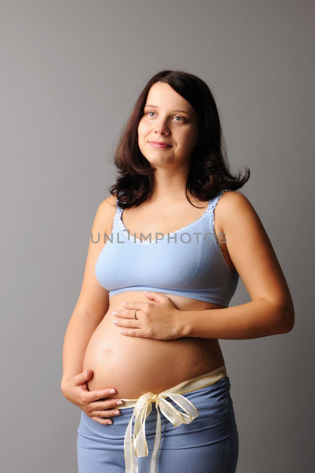 Portrait of a pregnant woman touching her belly with hands