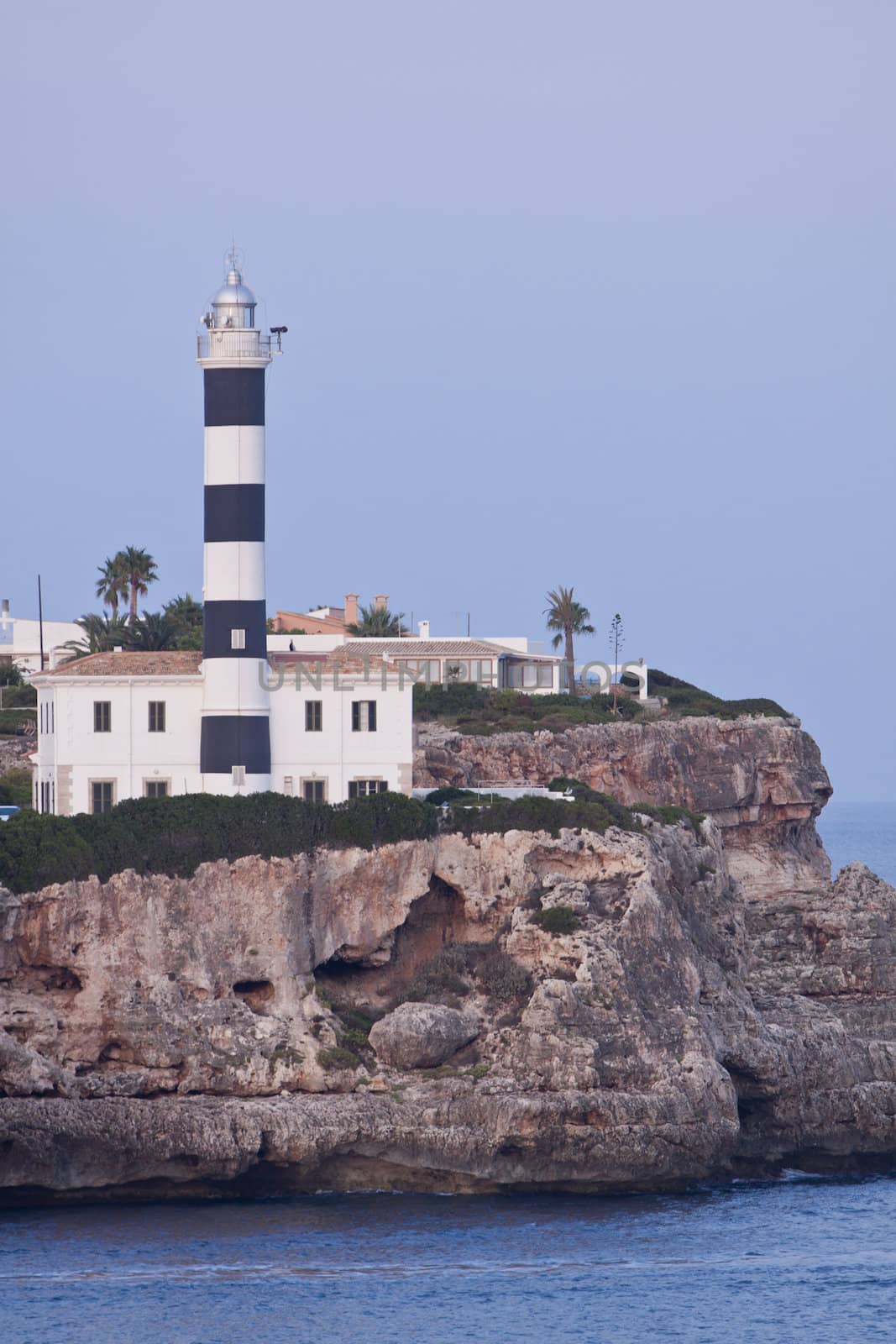 white lighthouse on rocks in the sea ocean water sky blue summer