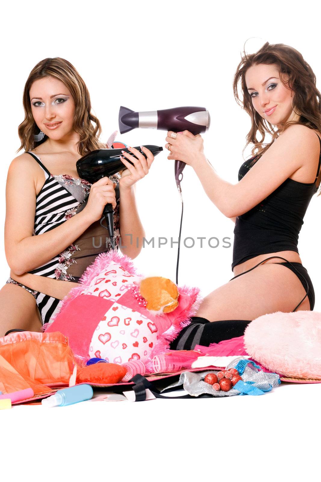 Two playful young girlfriends with hair dryers. Isolated