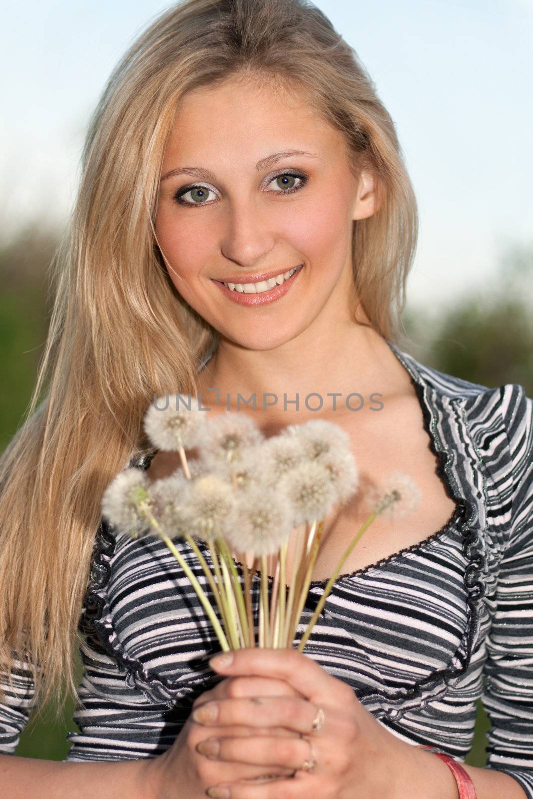Portrait of young attractive blonde with a dandelions