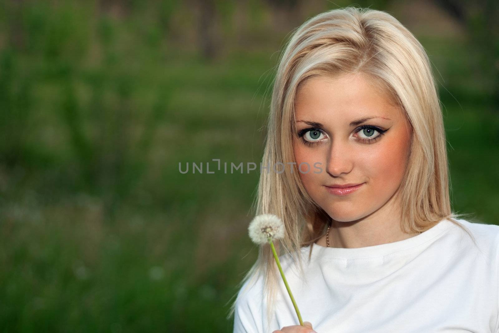 Portrait of young lovely blonde with a dandelion