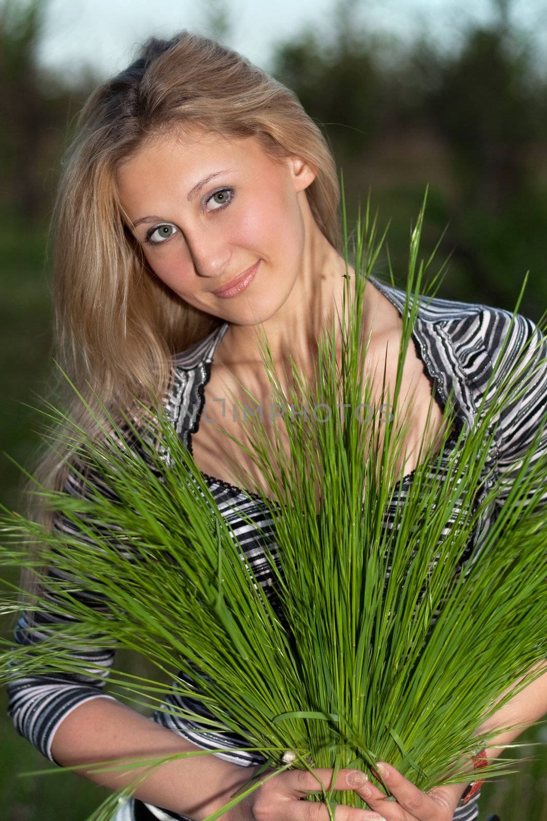 Young attractive blonde with green grass in their hands
