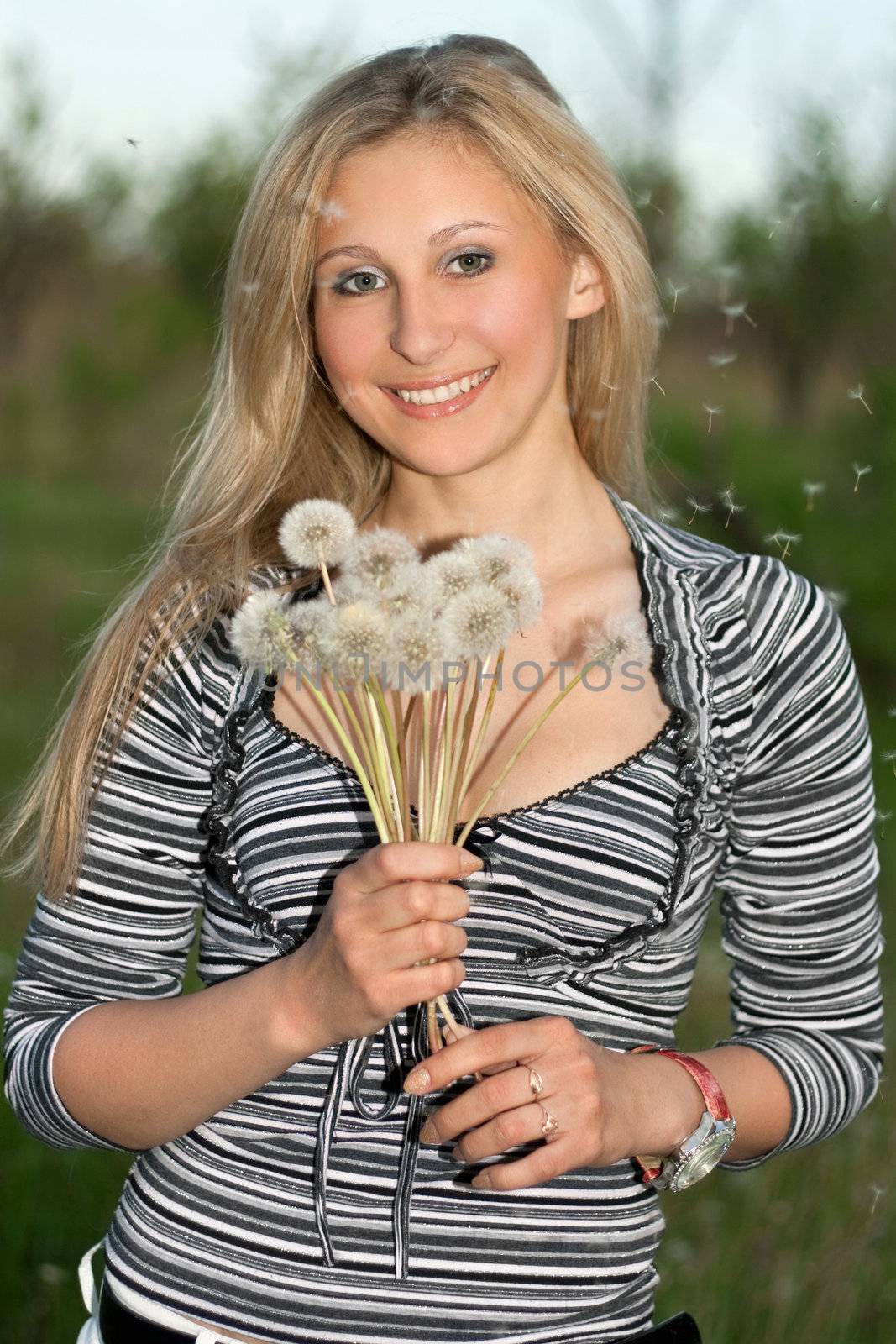 Portrait of cheerful young blonde with a dandelions