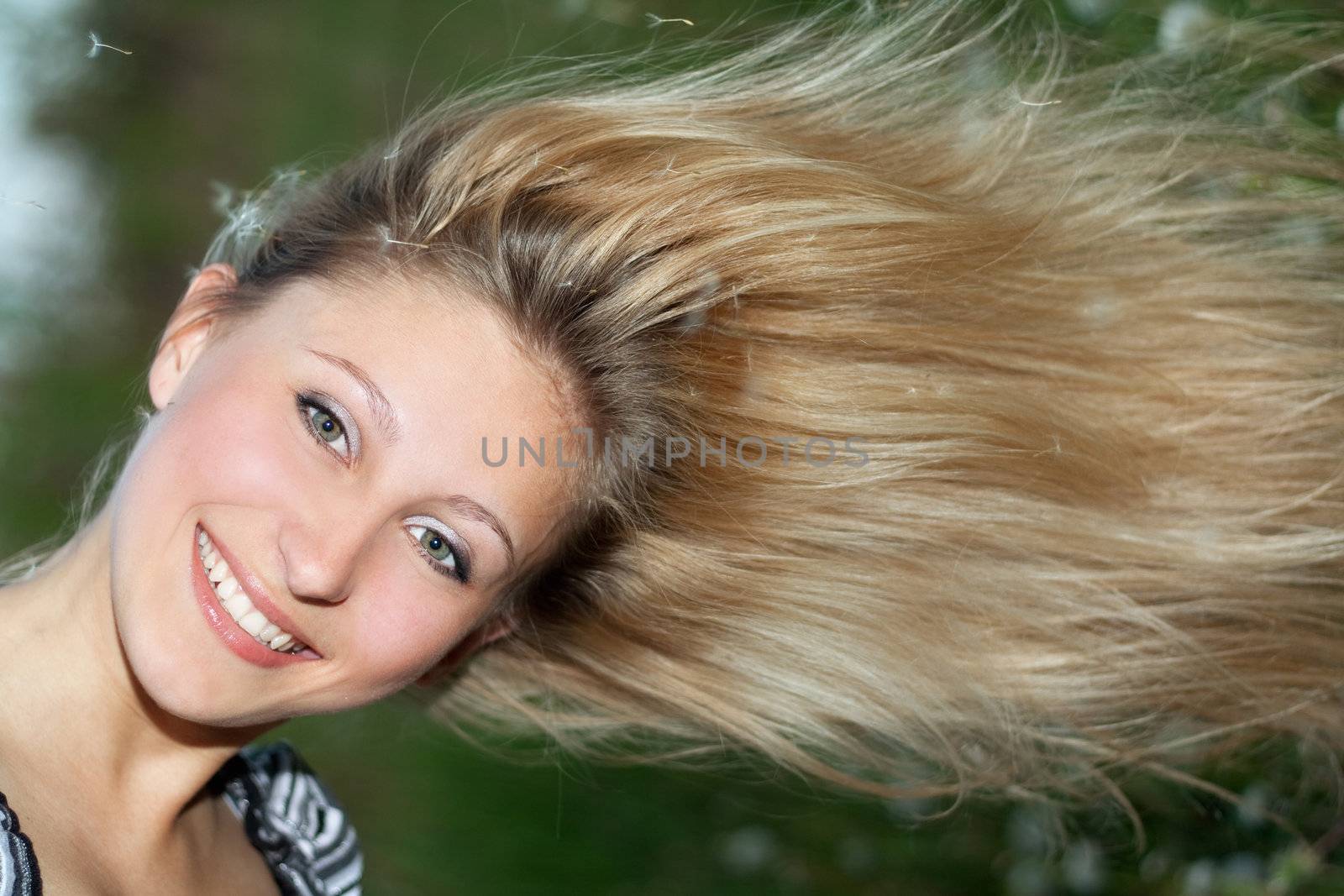 Cheerful young blonde in the seeds of dandelions