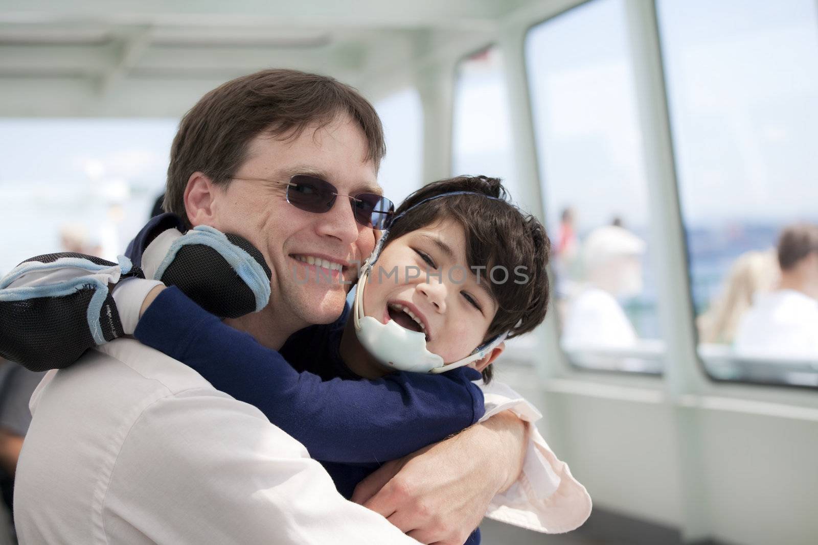 Father hugging disabled son as they ride a ferry boat by jarenwicklund