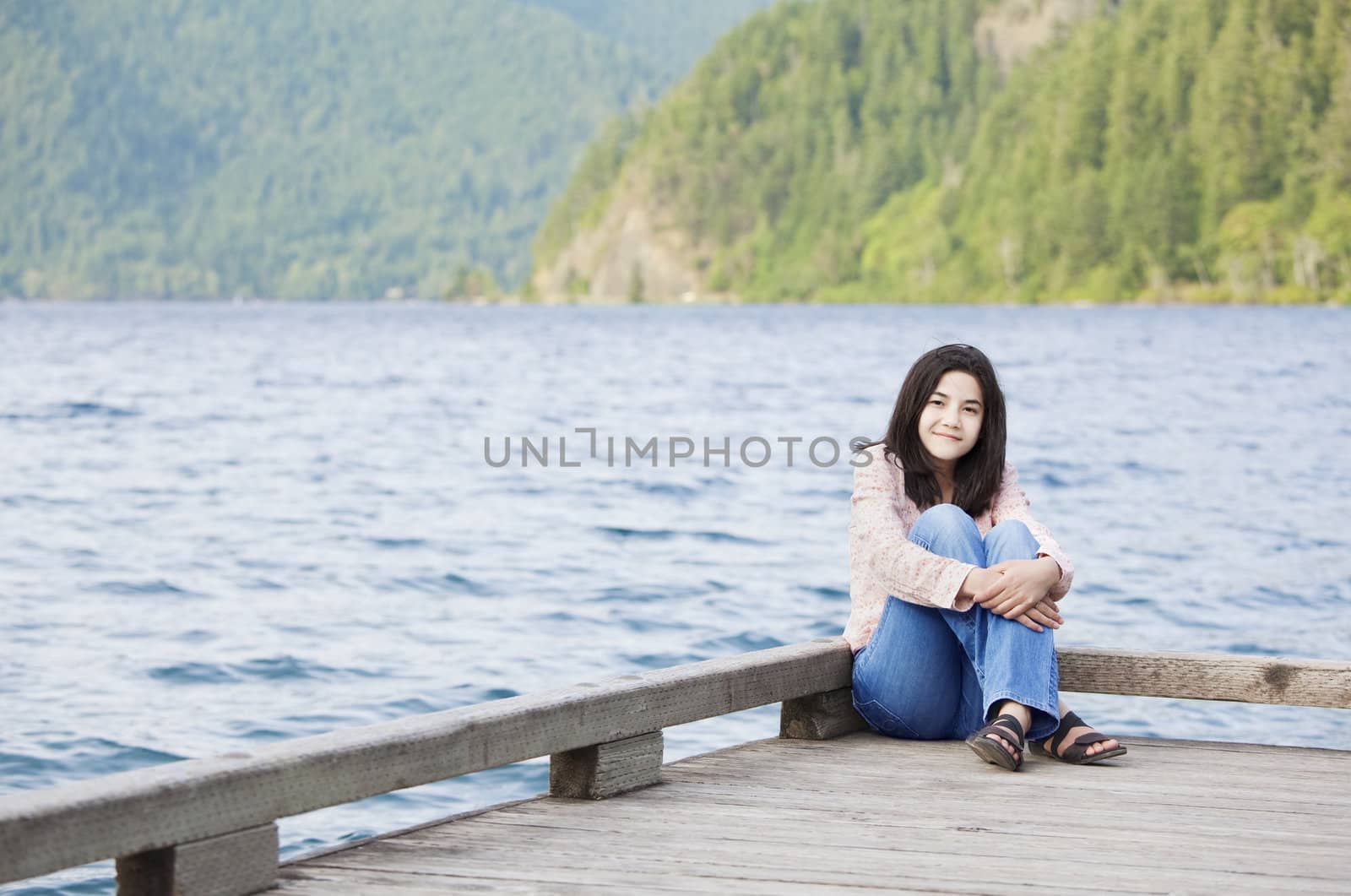 Young teen girl sitting quietly on lake pier, relaxing by jarenwicklund