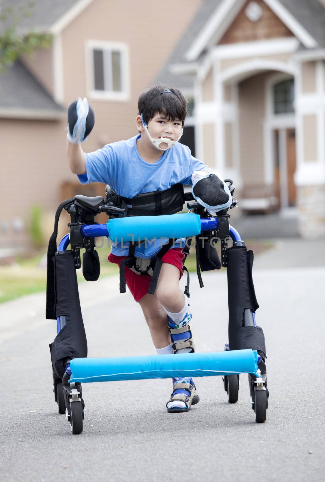 Six year old disabled boy walking in walker down the street by jarenwicklund