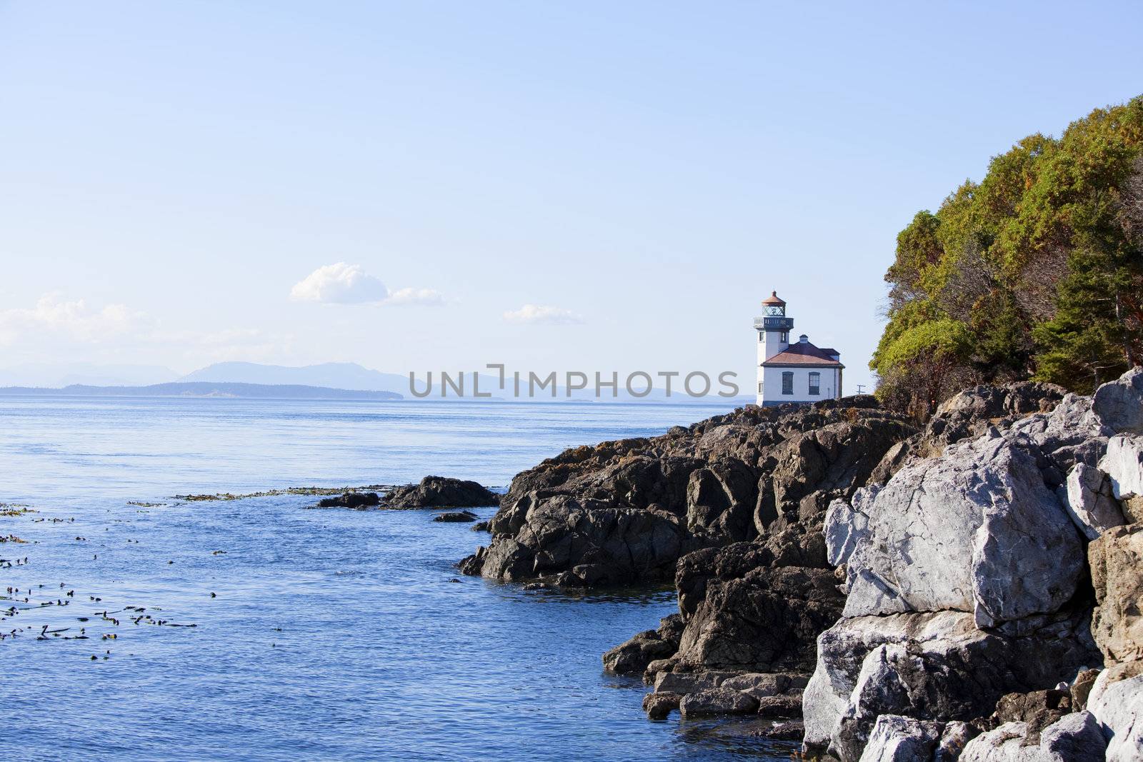 Blue waters of coast of San Juan island, Washington state. Lighthouse at Whale Watch Park in background