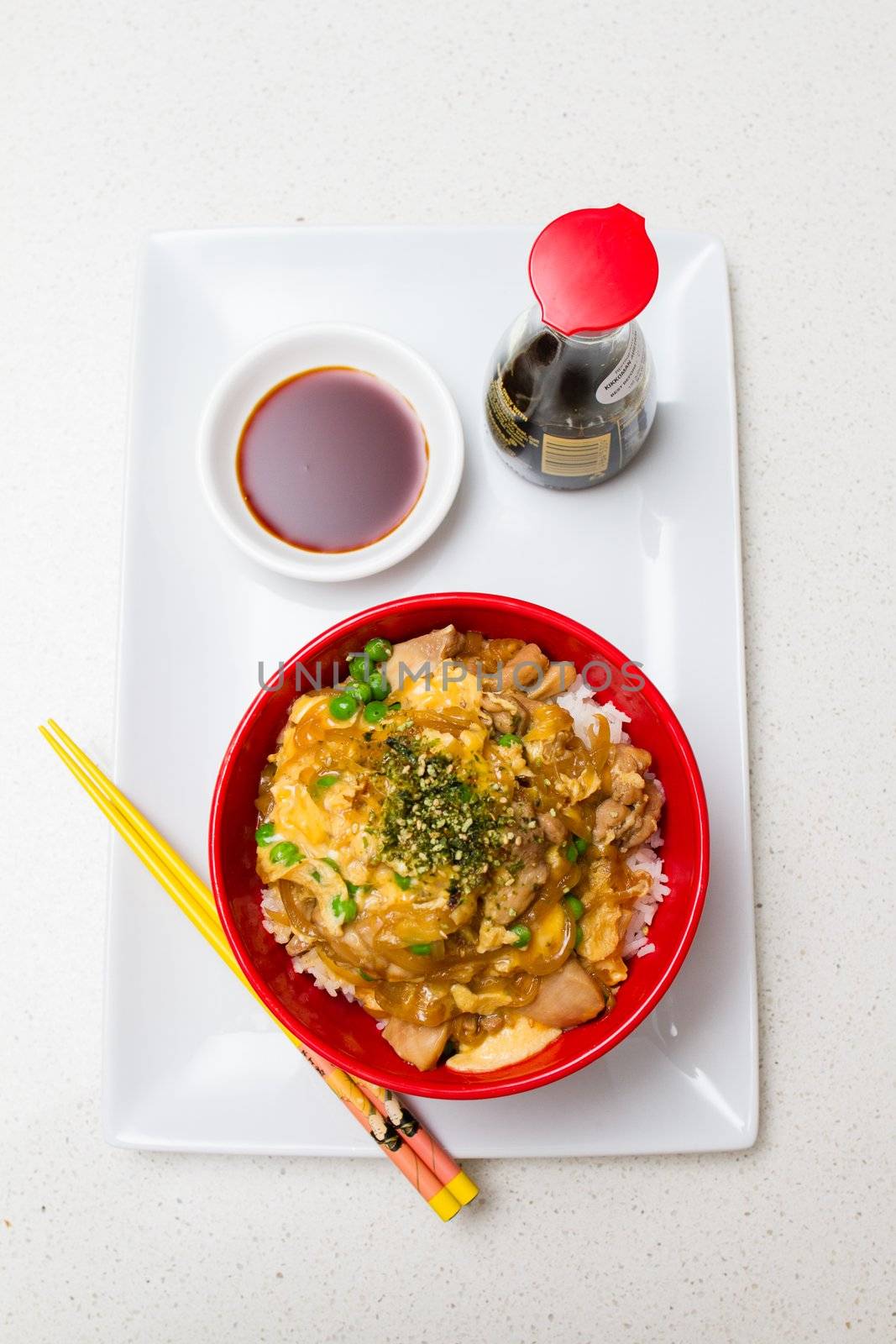 Oyako-don - Japanese checken rice in a red bowl with yellow chopsticks