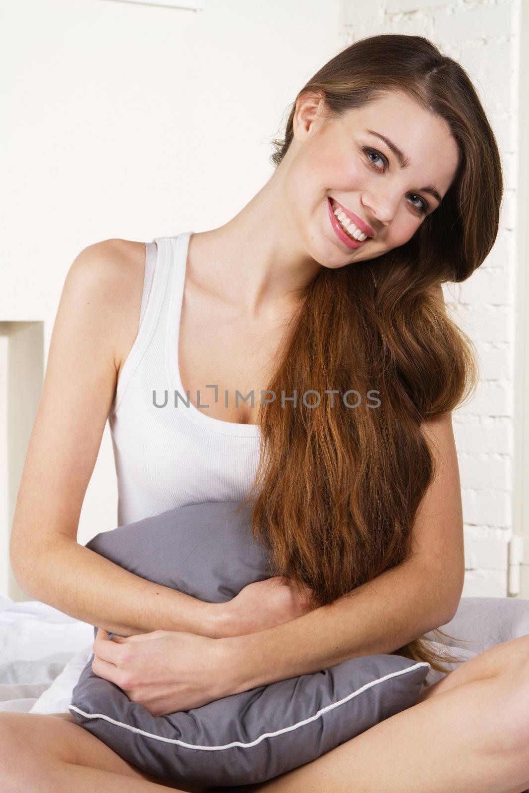 Young beautiful woman sitting with a pillow in bed 