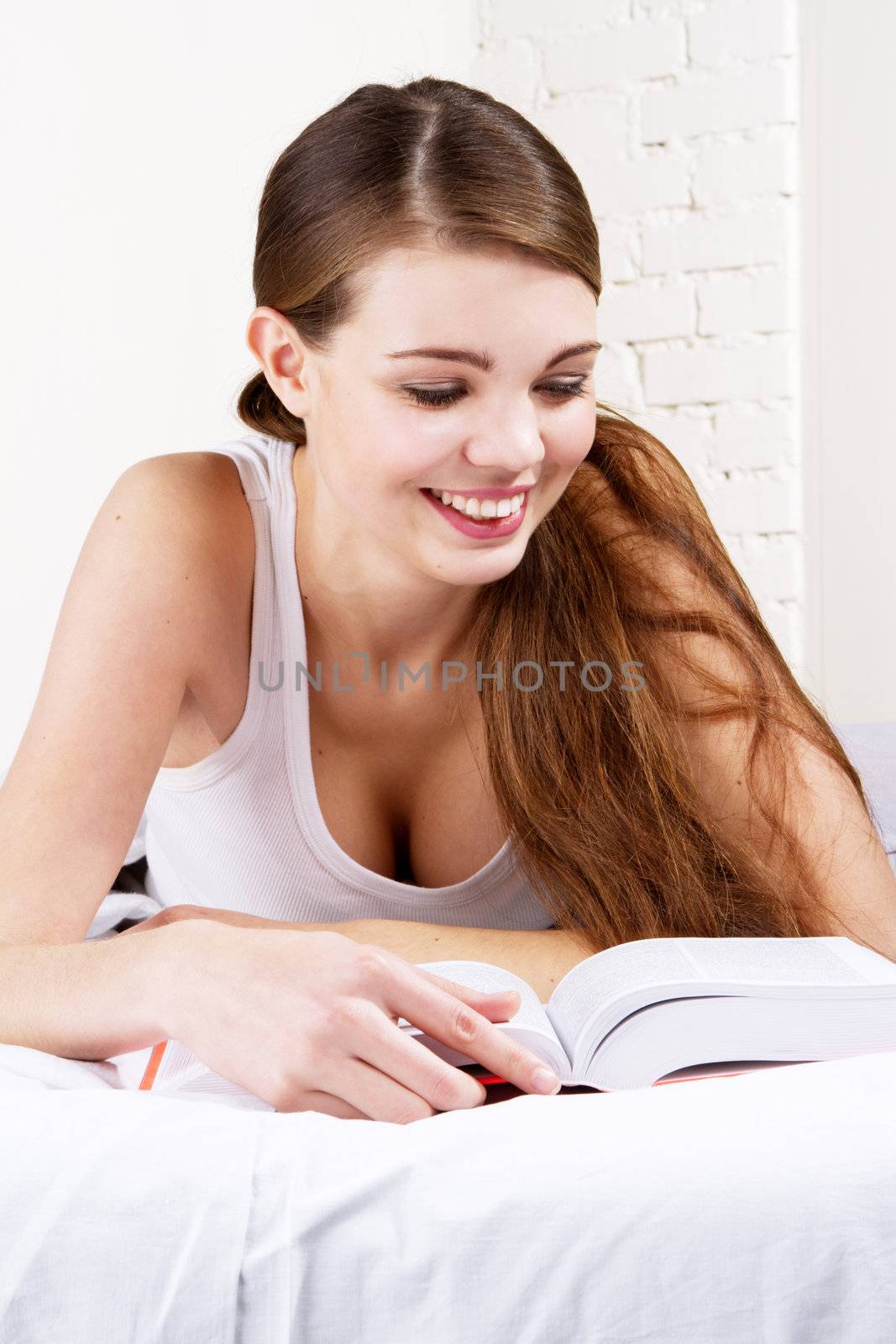 Young beautiful woman reading a book in bed 