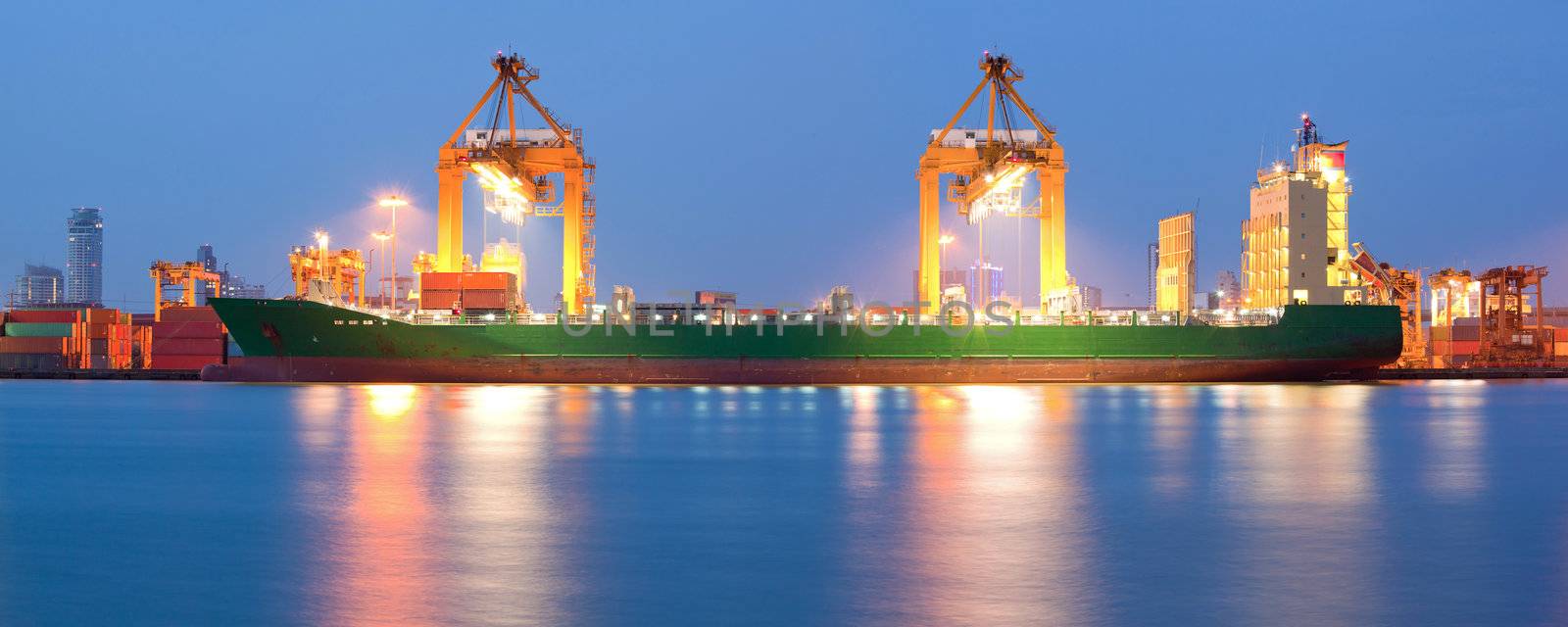 Panorama of Container Cargo freight ship with working crane bridge in shipyard at dusk for Logistic Import Export background