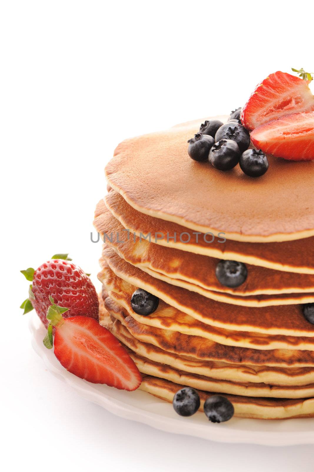 Delicious freshly prepared pancakes with strawberry and blueberries isolated on white