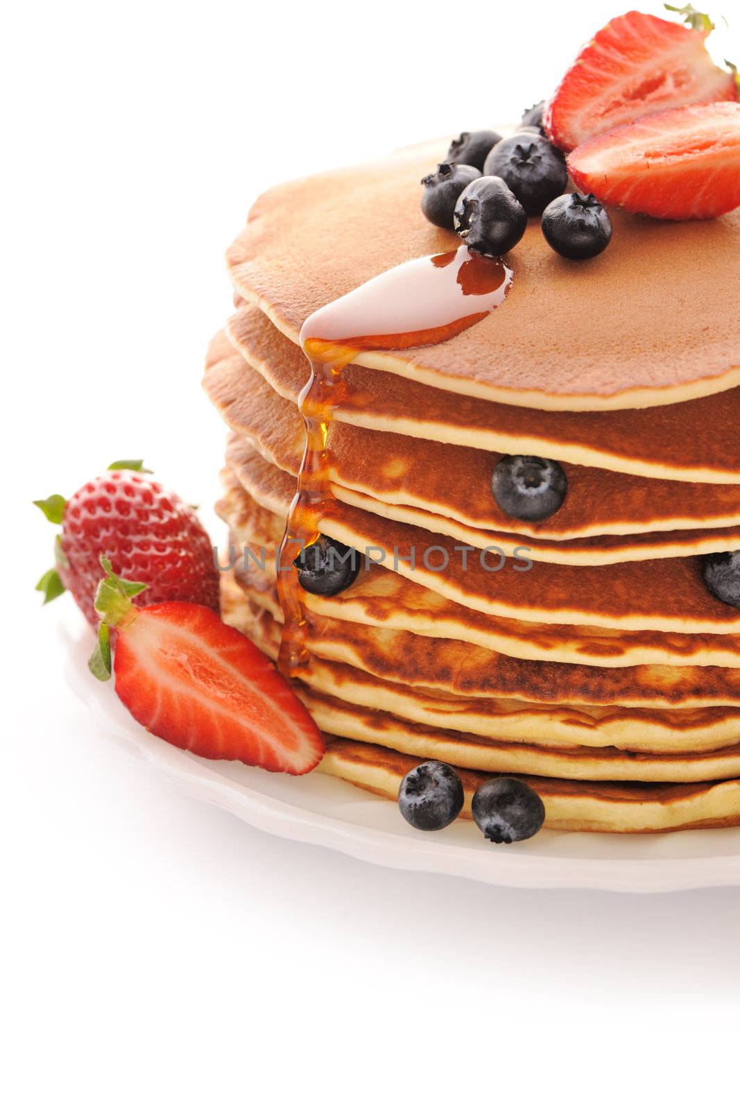 Delicious freshly prepared pancakes with strawberry and blueberries isolated on white