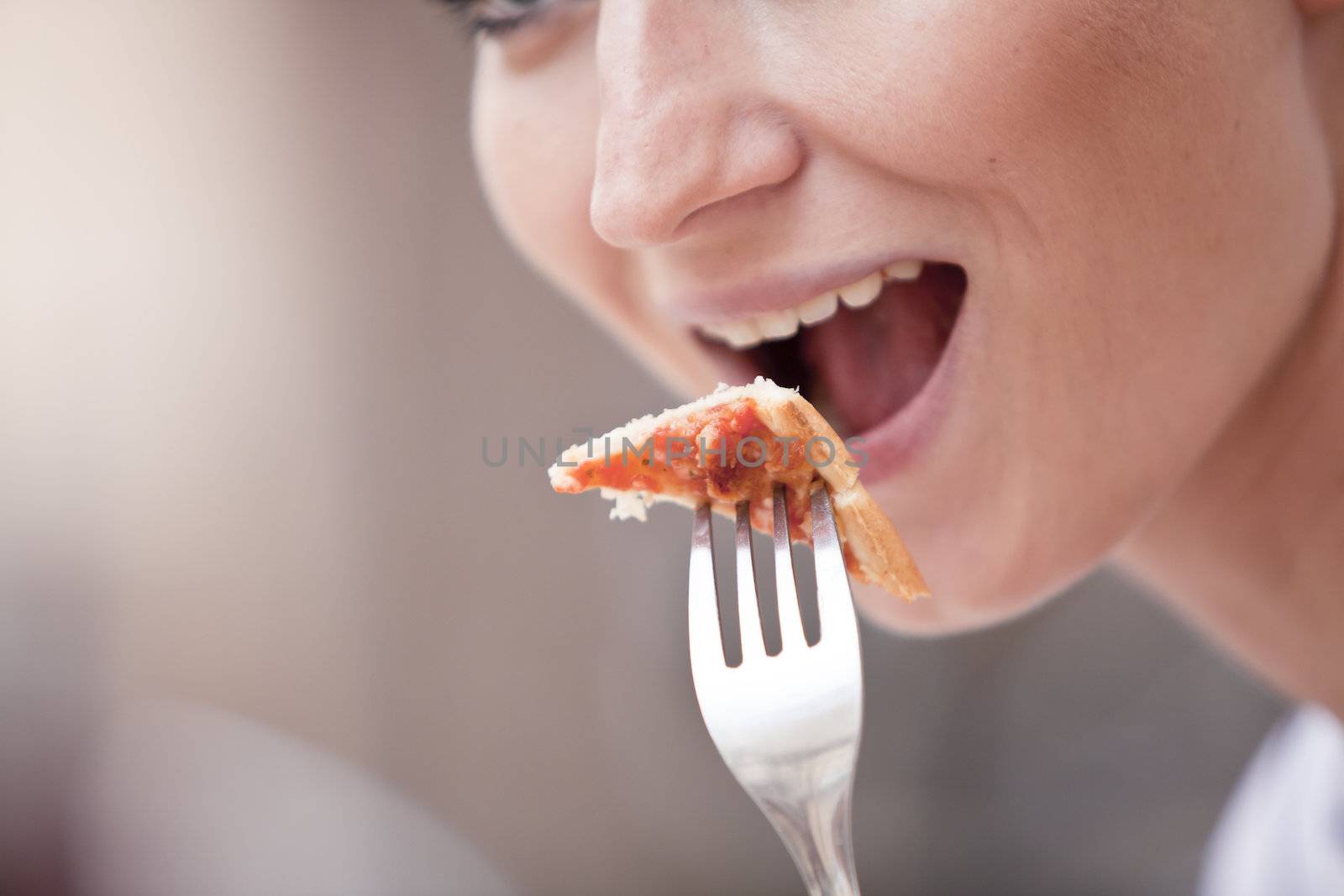 young woman is eating a pizza in restaurant by juniart