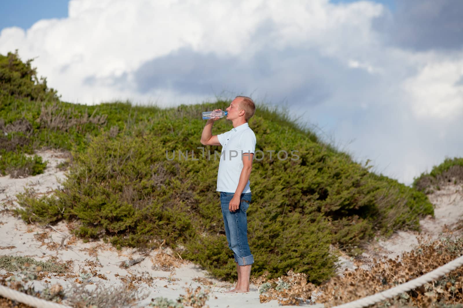 young man ist drinking water summertime dune beach sky by juniart