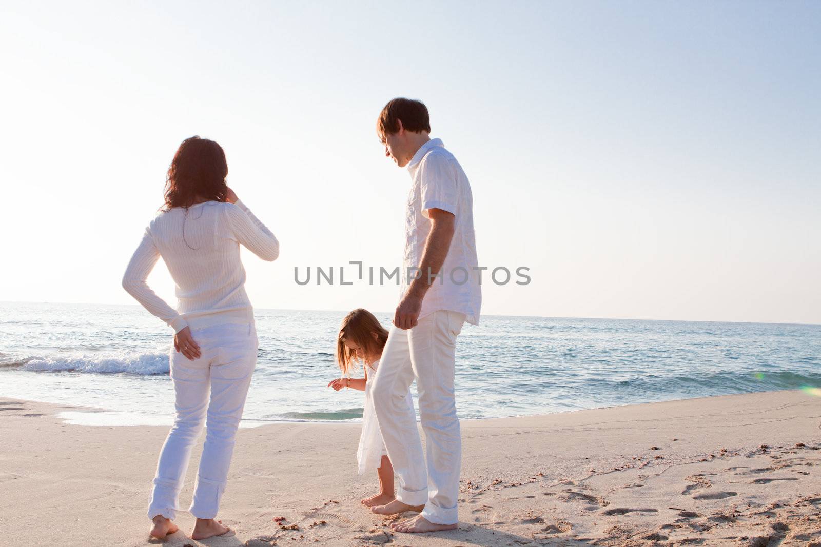 happy young family with daughter on beach in summer lifestyle