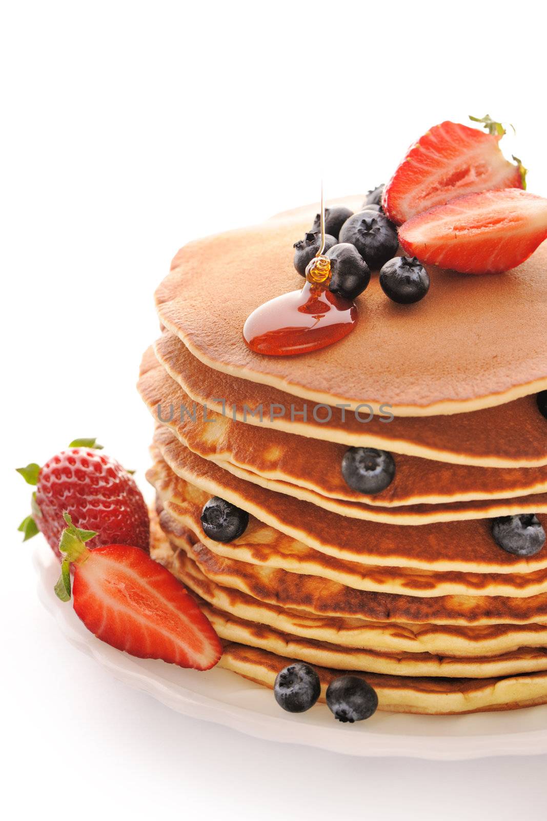 Delicious freshly prepared pancakes with strawberry and blueberries isolated on white